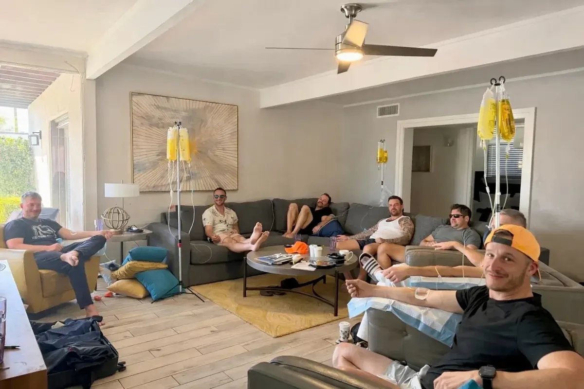 A group of friends spread across the sofas of a Phoenix living room, all on drips, stands standing between them